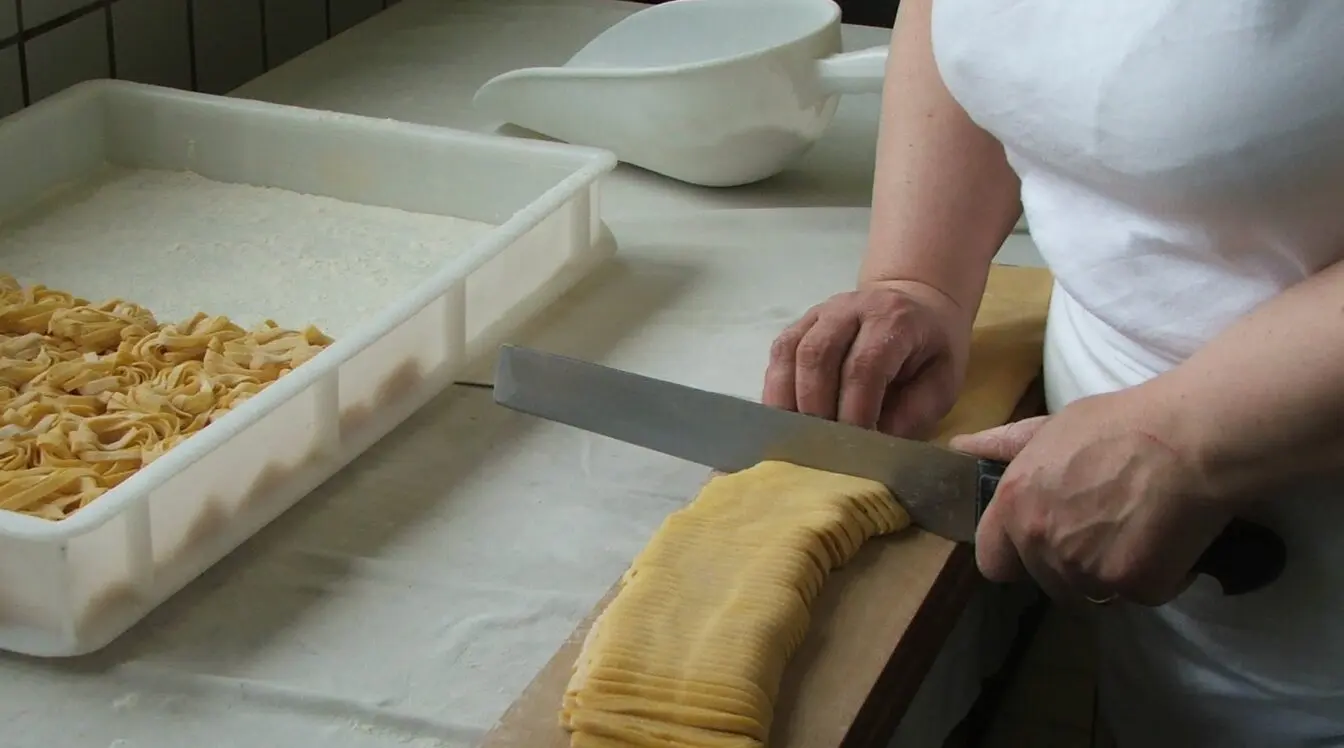 Fresh pasta being cut by hand during a traditional Italian cooking experience