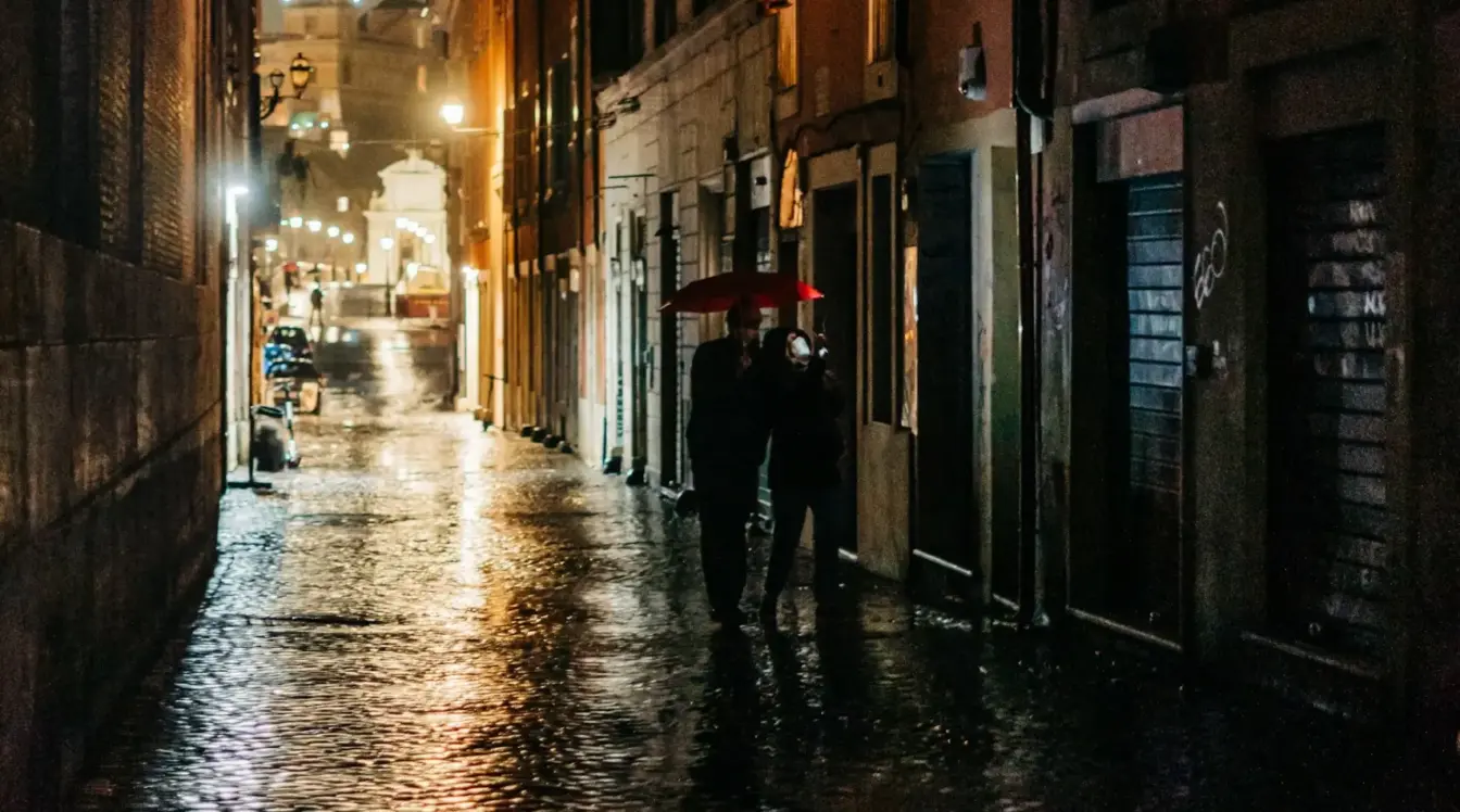 Couple walking under an umbrella on Via dei Pettinari in Rome